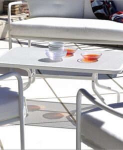 Outdoor furniture with a white Outdoor Traditional Coffee Table, dishes on top, and a white sofa in the background
