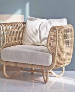 Rattan Club Chair — Modern wicker armchair with cushions in a stylish room with soft lighting
