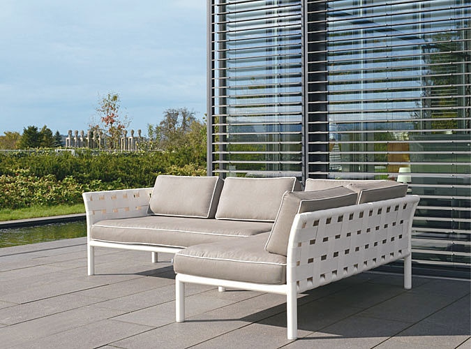 Pipe Strap Sectional Sofa — Modern outdoor Sofa on a patio with greenery and a building in the background.