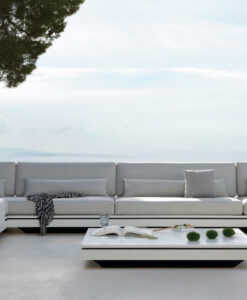 Manutti Elements Sectional Sofa — Modern outdoor sectional sofa with white cushions on a patio overlooking the sea.