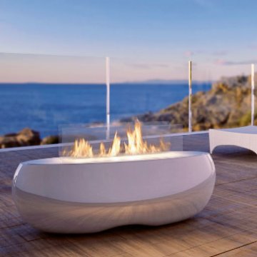 A sleek white fire pit with a glass-enclosed flame sits poolside in a modern indoor space.