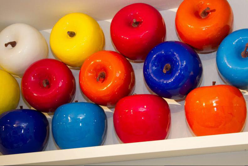 Colorful artificial apples are neatly arranged on a shelf