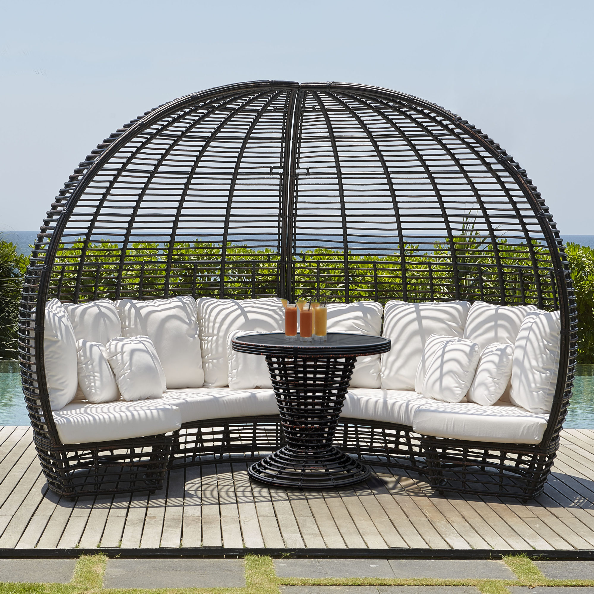 Nexus Collection — Outdoor round black wicker daybed with white cushions and table
