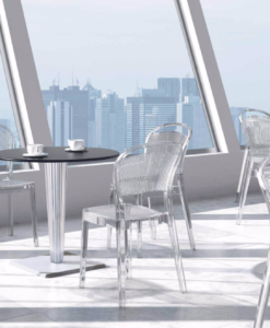 Miller Dining Chair — Modern cafe interior with transparent chairs, tables, and urban skyline view