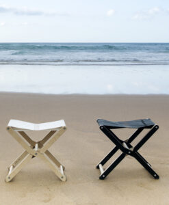 Two folding stools on beach sand with ocean