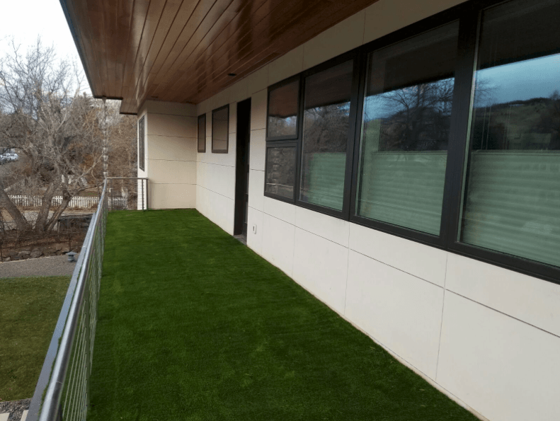 Long balcony with artificial grass and large windows on a modern building.