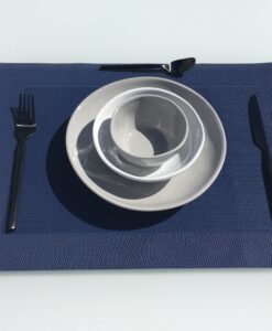 A neatly arranged table with stacked bowls, a black-handled fork on the left, a knife on the right, and a spoon at the top on a blue placemat.