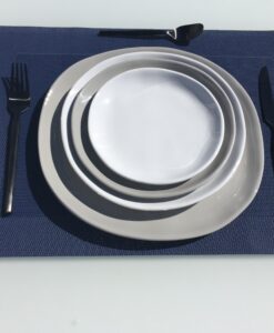 On the blue table mat, there is a stack of plates with a fork on the left, two knives on the right, and a spoon in front of the plates.