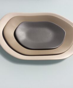 A stack of three nested Melamine Stone Oval Platters in shades of cream and gray on a light blue background.