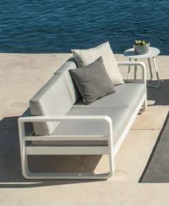 Modern outdoor lounge furniture on a patio by the sea.