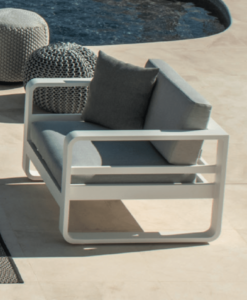 Rio 1 Club Chair: Modern outdoor chair with cushions next to two woven poufs by a pool.